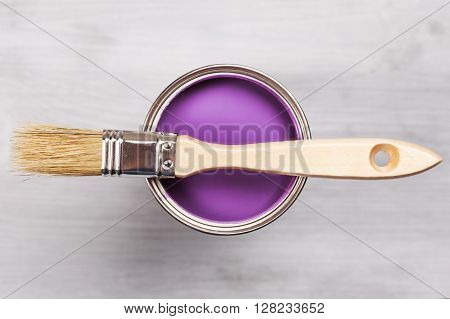Copyspace with paint brush and can with violette or lavender paint lying on white wooden clean table. Top view. Copyspace.