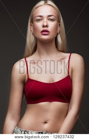sexy fashion model with long hair, young European attractive, beautiful eyes, full lips, perfect skin is posing in studio for glamour vogue test photo shoot showing different poses. Picture taken in the studio on a gray background.