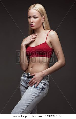 sexy fashion model with long hair, young European attractive, beautiful eyes, full lips, perfect skin is posing in studio for glamour vogue test photo shoot showing different poses. Picture taken in the studio on a gray background.