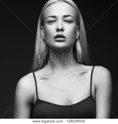 sexy fashion model with long hair, young European attractive, beautiful eyes, full lips, perfect skin is posing in studio for glamour vogue test photo shoot showing different poses. Picture taken in the studio on a gray background. Black and white photo