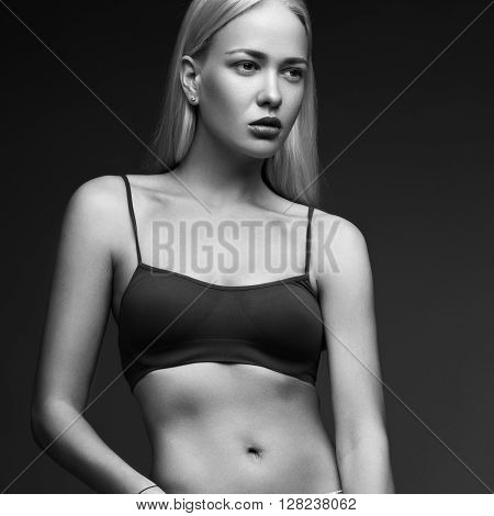 sexy fashion model with long hair, young European attractive, beautiful eyes, full lips, perfect skin is posing in studio for glamour vogue test photo shoot showing different poses. Picture taken in the studio on a gray background. Black and white photo