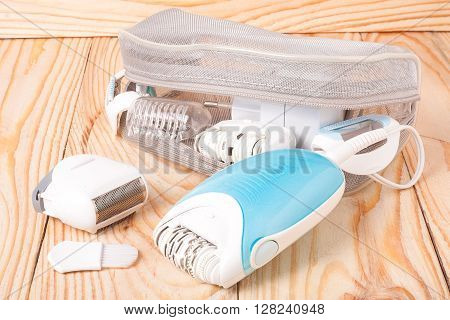 electric epilator hair on a light wooden background.