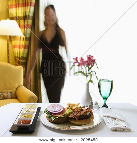 Pokojová služba cheeseburger jídlo s květinami a Tchajwanci polovina dospělé ženy v pozadí.