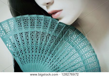 half face of asian woman with a green fan
