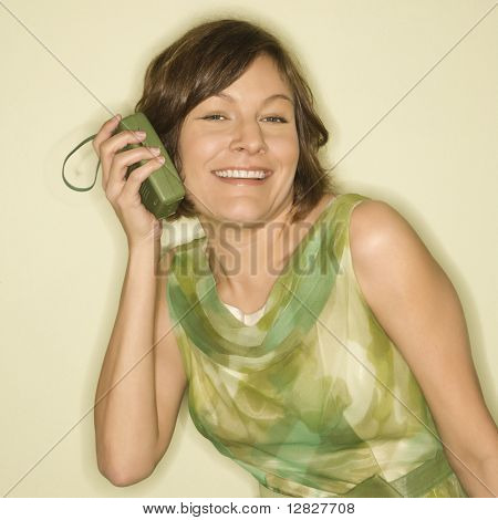 คอเคซัสสวย mid-adult ผู้หญิงที่สวมใส่เสื้อวินเทจสีเขียวถือวิทยุมือถือถึงหูของเธอเป็น
