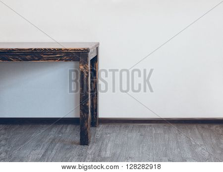 Part of empty wooden table in room over light wall with empty space
