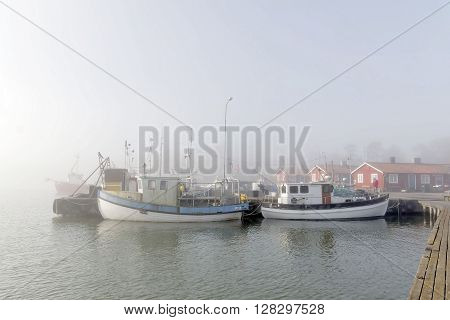GRISSLEHAMN SWEDEN - MAY 01 2016: Small fishing boats in the harbor a foggy morning in Grisslehamn Sweden