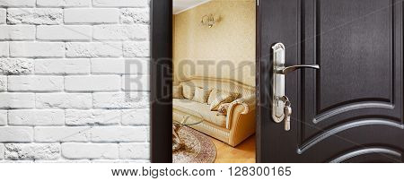 Half opened door to a living room. Door handle, door lock. Lounge door half open. Opening door. Privacy, safety concept. Entrance to the room. Door at white brick wall, modern interior design.