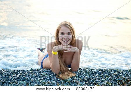 Young beautiful girl in a bathing suit lying on the beach on vacation