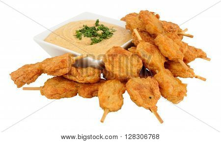 Chicken satay skewers with dish of peanut dip isolated on a white background
