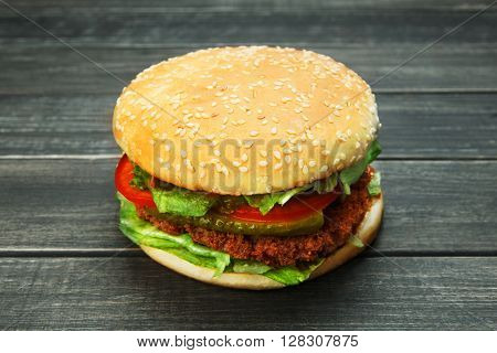 Classic american burger fast food. Big double burger at wood. Hamburger with fresh vegetables and meat. Burger with cheese, beef, tomato, lettuce. Cheeseburger at rustic wooden background.