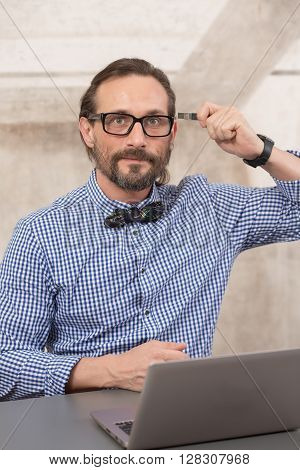 Handsome freelancer in glasses looking at camera and holding usb card near his head in office. Memery and storage concepts.