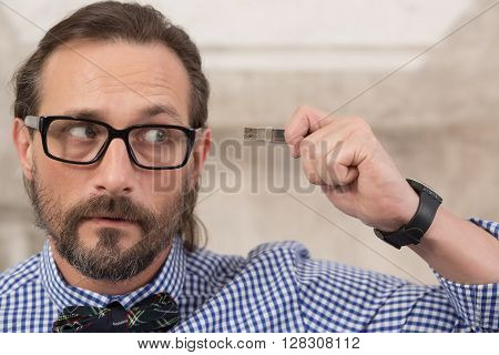 Close-up picture of handsome freelancer in glasses holding usb flash card and looking away. Storage, data, memory concepts.