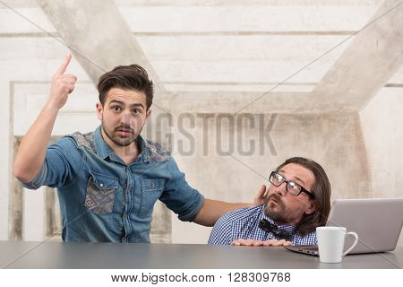 Frightened boss sitting under table and hiding from tax office while his worker explaining how to behave in difficult situations.
