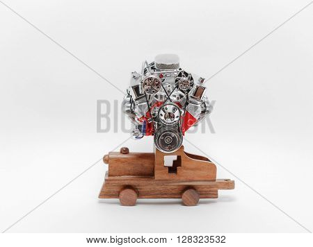 Old truck engine sitting on wooden vintage toy train against light-grey background