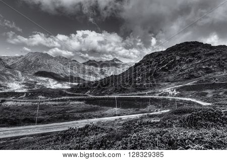 Beautiful curvy road passing through Jelepla Pass Dzuluk Sikkim India -with blue sky and clouds in the background. Black and white image