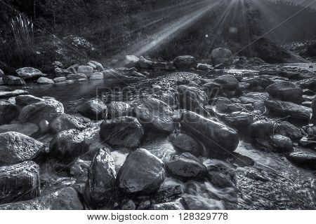 River water flowing through rocks at dawn sun light beams on the water beautiful Reshi River Sikkim India - black and white stock image of rivers in India