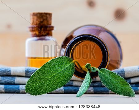 Bottle Of Essential Oil With  Fresh Sage Leaves Shallow Depth Of Field On Old Wooden Background.