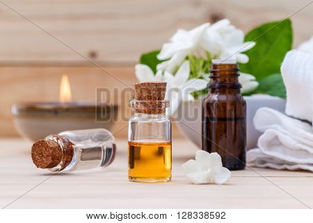 Bottle Of Essential Oil And Jasmin Flower With Shallow Depth Of Field Setup On Wooden Background .