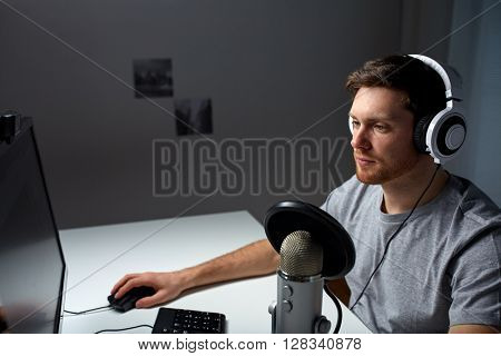 technology, gaming, entertainment, let's play and people concept - young man in headset with pc computer playing game at home and streaming playthrough or walkthrough video