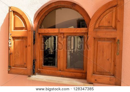 Wooden window with two shutters in arc of brown color.