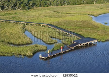 Luftfoto af to teenagedrenge fiskeri fra dock i sumpede lavlandet af Bald Head Island, North Caro