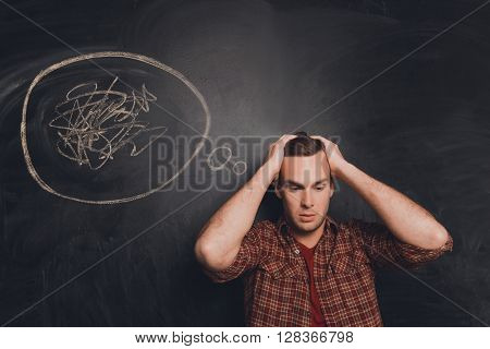 Young Tired Man At A Loss On The Background Of Chalkboard