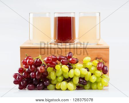Glass of red stum and 2 glasses of white stum together with some green and red grapes photpgraphed in the studio.