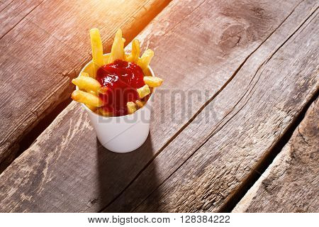 Cup of fries with ketchup. French fries with tomato sauce. Portion of fries on table. Special sauce for snacks.