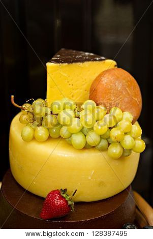 Still life photo with a head of cheese strawberry grape etc
