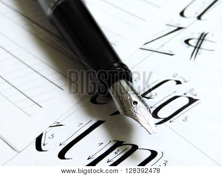 Calligraphy equipment, writing. Fountain pen and lined paper with alphabetic letters.