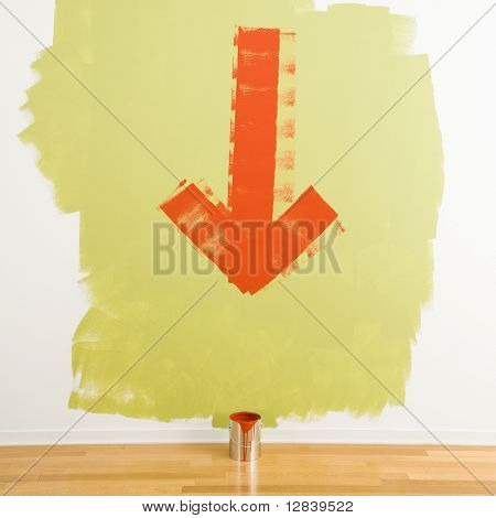 Freccia rossa dipinta sul muro puntando per la latta di vernice sul pavimento.