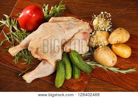 Raw chicken with vegetables on a wooden table