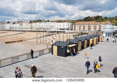 HASTINGS, ENGLAND - APRIL 30, 2016: People walk on the historic Victorian pier. Closed since 2008 and badly damaged by fire in 2010,  the landmark building reopened to the public on April 27, 2016.  