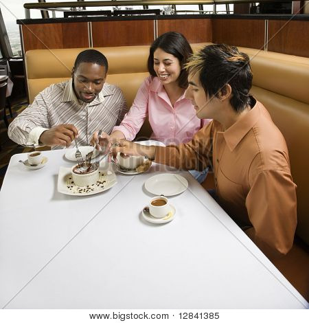 Pequeno grupo de amigos adultos meados compartilhamento de sobremesa em um restaurante.