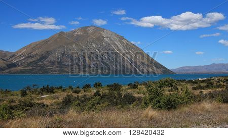 Turquoise water of Lake Ohau. Clouds over a peak of the Ben Ohau Range. Landscape in New Zealand.