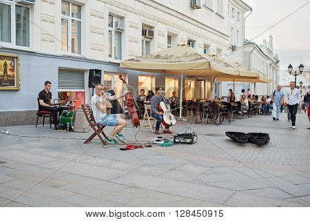RUSSIA, MOSCOW - JUN 22, 2015: People walk along Kuznetsky Most street near outdoor cafe with live music.