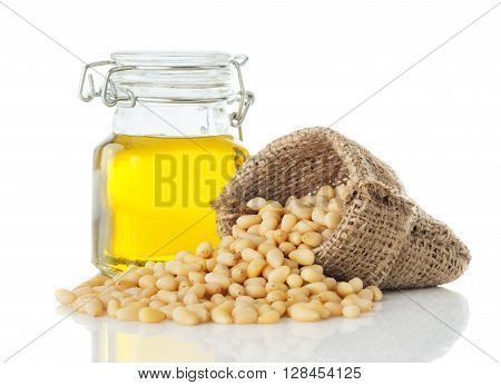 cedar oil in a glass jar and peeled pine nuts closeup isolated on white background