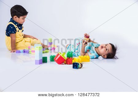 two indian kids playing with plasstic blocks