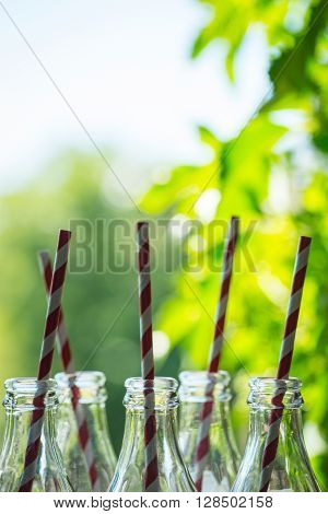 Glass Bottles With Straws Over The Sunny Background