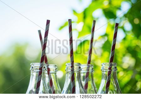 Glass Bottles With Straws Over The Sunny Background