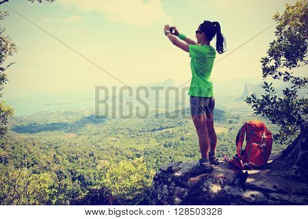 young woman hiker use smartphone taking photo on seaside mountain top