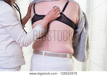 female doctor is listening to lunge of female patient