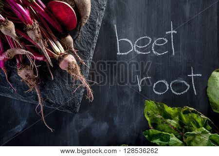 Bunch of beetroots on the stone and blackboard with chalk notes
