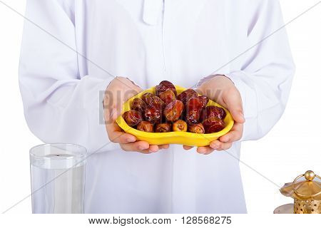 Little Muslim kid presenting a dish of dates for iftar - breaking fast in Holy Ramadan