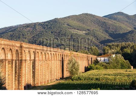 Section of the Nottolini Aqueduct in Tuscany near Lucca Italy leading to the mountains. Warm evening light with classic Tuscan textures and tones. Concepts could include Travel Architecture Europe others.