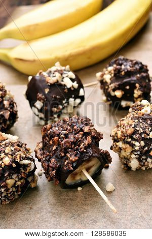 Summer dessert snack frozen banana covered with chocolate and peanuts