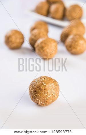 tilgul laddu or til gul laddu spread over white background, selective focus, single laddu isolated, showing texture
