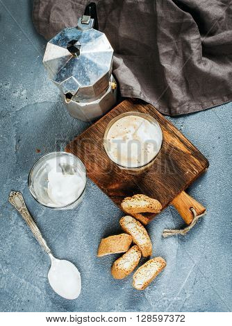Glasses of coffee with ice cream on rustic wooden board, steel Italian Moka pot over grey concrete textured background, top view