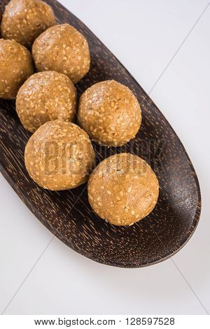 wooden plate full of tilgul laddu or til gul laddu over white background, selective focus